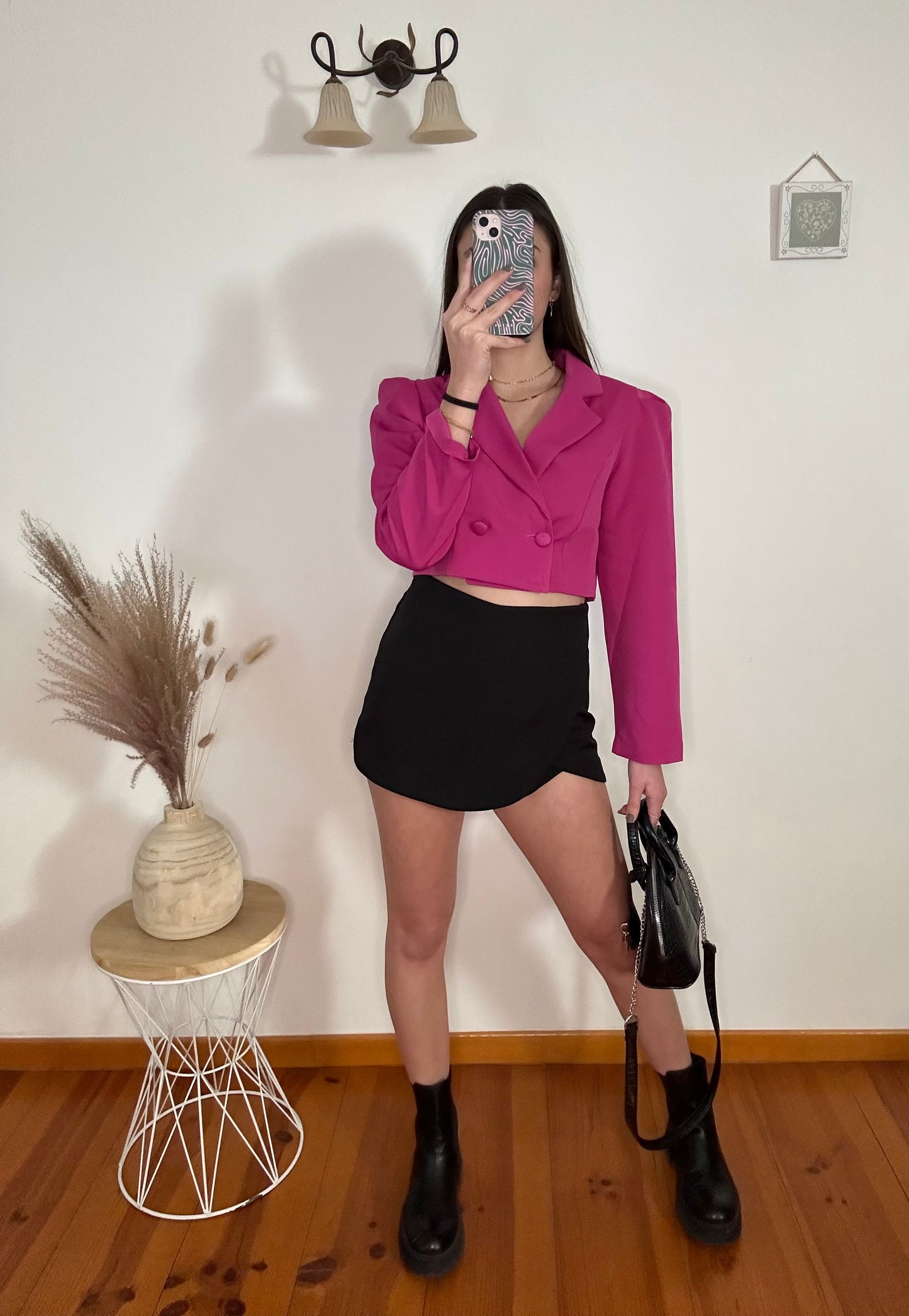 Femme portant une jupe short noire avec un blazer rose court fabriqué en Italie. 